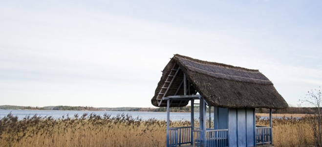 Bild på ett litet blått hus med havet i bakgrunden