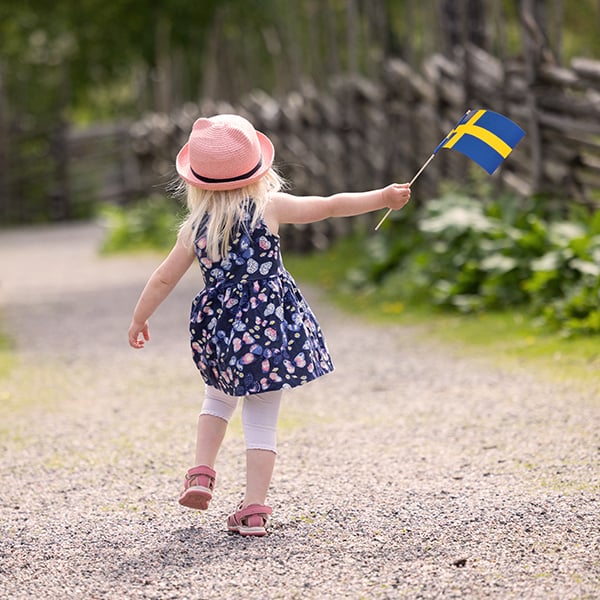Flicka som går med en liten svensk flagga.