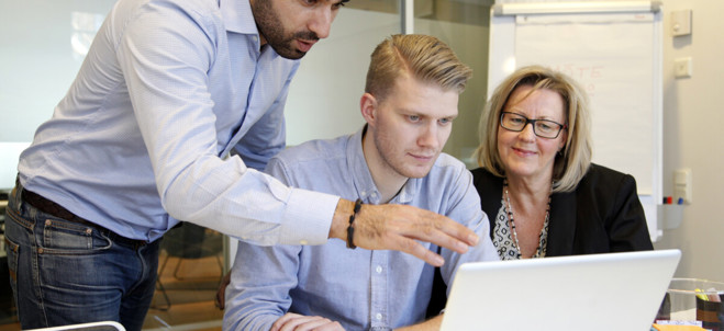 Tre personer diskuterar innehållet på en dator