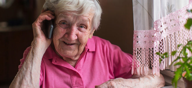 äldre kvinna talar i telefon i sitt hem