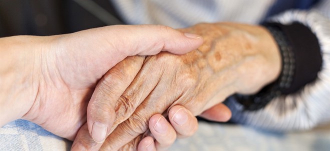 Händer som håller i varandra, en äldre person och en yngre person.
