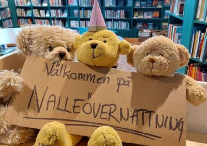 Tre teddybjörnar håller upp en skylt med 'nalleövernattning'