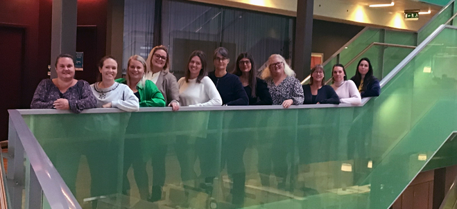 Pristagarna stående på rad bakom ett grönt räcke.