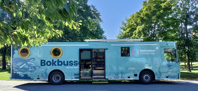Ljusblå buss parkerad utomhus med träd i bakgrunden