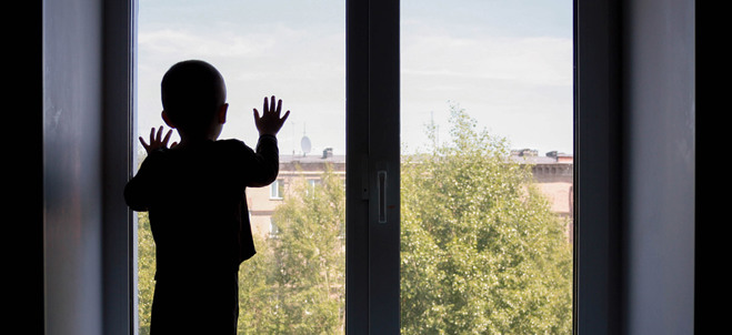 Ett barn tittar ut ur ett fönster