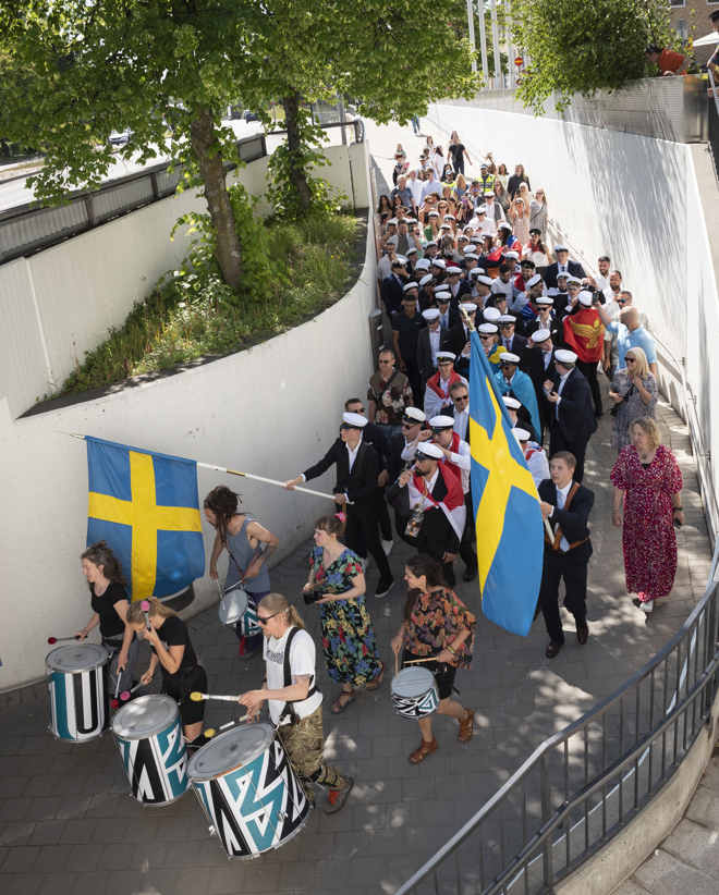 Många unga studenter tågar med flaggor och musikinstrument från Stadshuset till Stadsparken