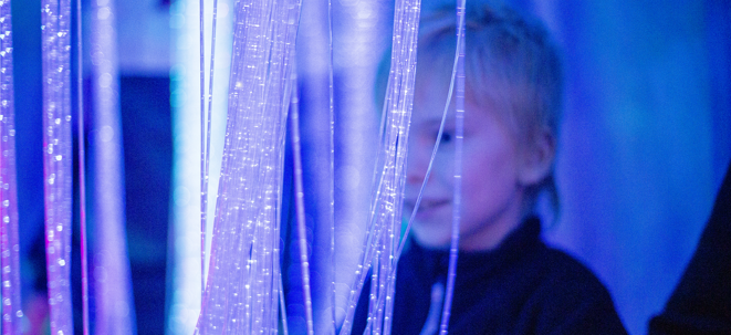 En pojke står bakom ljusslingor. Bakgrunden  är  blå.