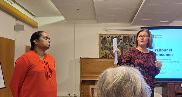 Två kvinnor står upp vid en bildskärm och håller en presentation