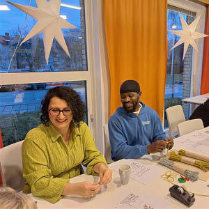 Bild på två kvinnor och en man som julpysslar vid ett bord.