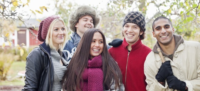 Bild på fem ungdomar i övre tonåren i en trädgård eller liknande.