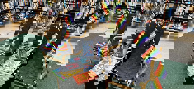 pridehörna vid bibliotekshyllor med flaggor och hbtqi-litteratur och information
