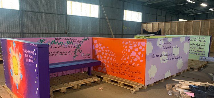 Bild på större möbel med flera bänkplatser; byggd och målad i färgstarka motiv av ungdomar. 