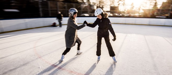 Två personer som åker skridskor i en utomhusrink