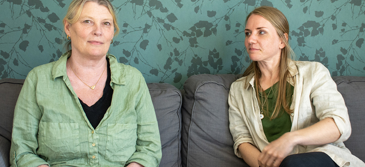 Porträttbild på två kvinnor som sitter i en soffa.