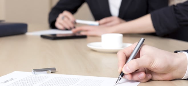 foto, två personer sitter vid bord och skriver på anteckningsblock