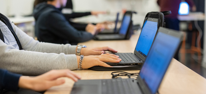 Elever sitter framför sina datorer i ett klassrum.