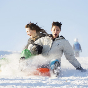 Två kvinnor åker pulka i nedförsbacke