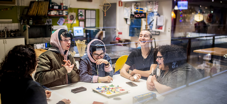 Bilden visar fem glada ungdomar runt ett bord på mötesplats Nova, Södertälje stadsbibliotek.