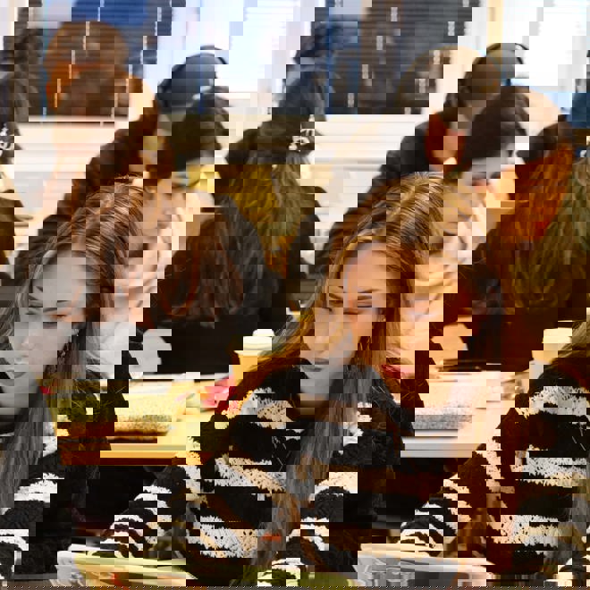 studerande vid skrivbord i ett klassrum, både kvinnor och män