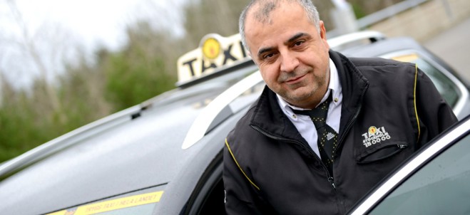Närbild på en taxichaufför och en taxi i Södertälje.