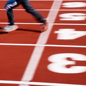 Bild som visar en löpare som springer, vi ser ben och fötter avteckna sig mot en löparbana.