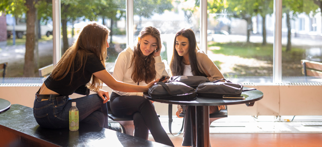 Tre tjejer sitter vid ett bord.