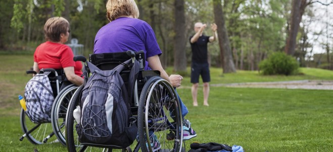 Två personer i rullstol. Bilden är tagen bakifrån.
