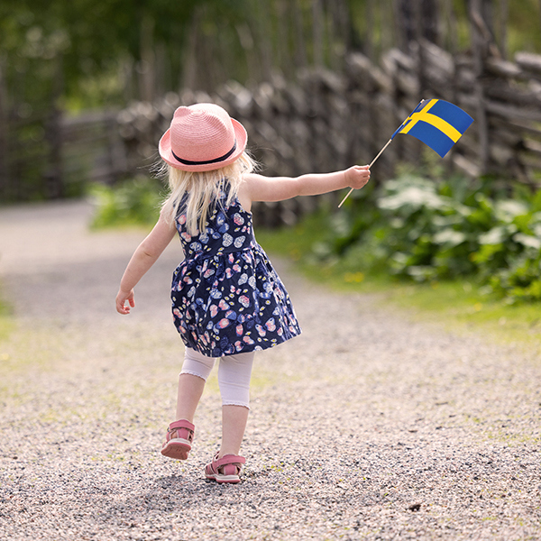 Flicka som går med en liten svensk flagga.
